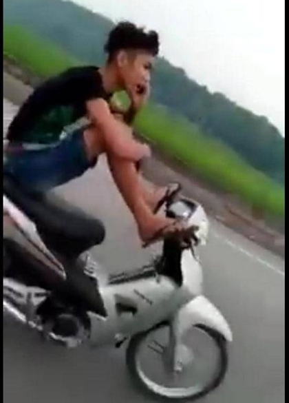 Nam thanh niên điều khiển xe máy bằng 2 chân, tay cầm điện thoại khoe với mẹ đang lái xe an toàn - Ảnh cắt từ clip