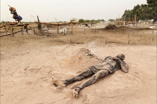 
Người đàn ông nằm thư giãn trên đống tro xốp màu hồng đào, bên cạnh một đống lửa đốt trên phân bò.
