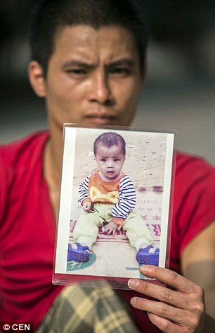 
Anh Shengkuan giơ ảnh chụp con trai trước khi cậu b&eacute; bị bắt c&oacute;c. Ảnh: reporterindia.
