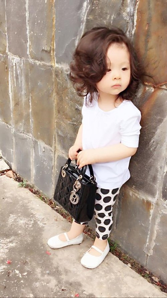 Trong một hình ảnh street style, bé Mộc Trà mặc bộ đồ như fashionista thứ thiệt với quần họa tiết chấm bi, áo trắng, giày trắng. Chiếc túi Lady Dior của bé có giá trị khoảng hơn 60 triệu đồng.