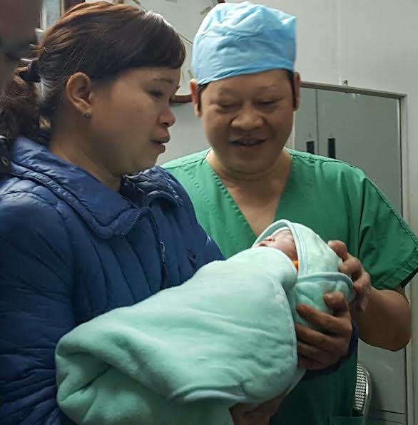 
GS Tiến bên bé gái được sinh ra từ ca mang thai hộ đầu tiên ở BV Phụ sản Trung ương. Ảnh: H.Hải
