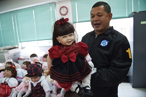 Một cảnh sát khám búp bê luk thep sau khi tịch thu 100 con trong các cuộc truy quét. Ảnh: Reuters