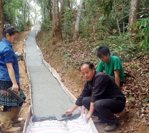 Phó Chủ tịch UBND xã Hoàng Thu Phố - anh Tráng Seo Pao - cùng người dân làm đường bê tông (Ảnh TL)