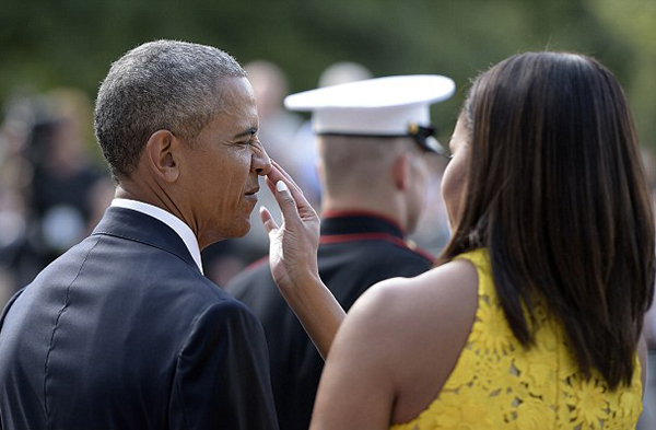 
Trước cử chỉ tình cảm của vợ, ông Obama khẽ nheo mắt và để yên cho vợ lau. Ảnh: AFP
