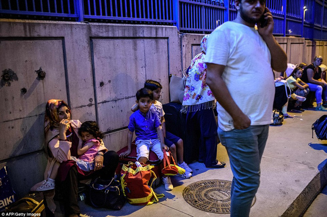 
Các gia đình đang chờ đợi bên ngoài nhà ga với hành lý của họ sau khi tất cả các máy bay bị hủy sau vụ tấn công.
