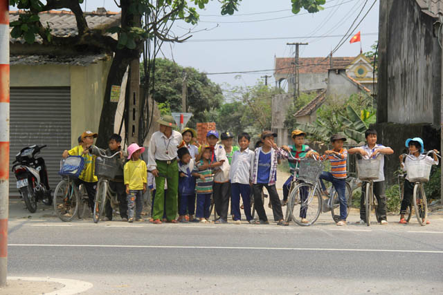 
Đôi mắt của ông luôn phải đảo qua đảo lại liên tục cho tới khi vắng xe mới cho các em qua đường. Ảnh: Phan Ngọc
