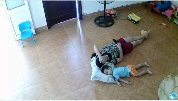 
Hình ảnh em bé ngủ trên sàn với người giúp việc để bà tiện xem ti vi buổi trưa.
