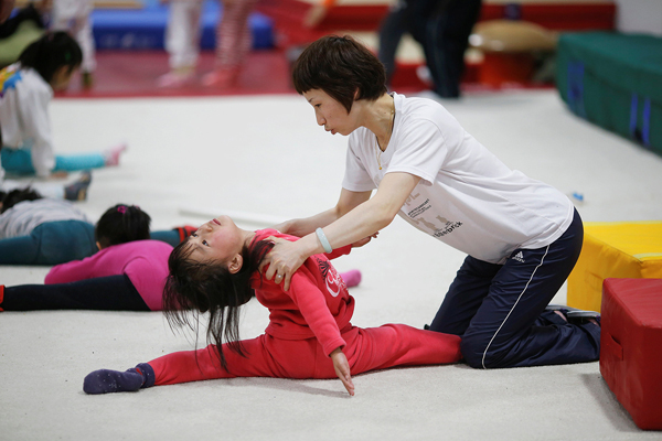 
Một bé gái được cô giáo hướng dẫn thực hiện động tác khó trong giờ tập. Trung Quốc nổi tiếng thế giới bởi có nhiều cơ sở, lò luyện trẻ khắc nghiệt, đào tạo chúng thành những người có thể gặt hái được huy chương vàng. Tại thế vận hội diễn ra ở Bắc Kinh năm 2008, nước chủ nhà Trung Quốc đã đạt được nhiều huy chương vàng chỉ sau Mỹ.
