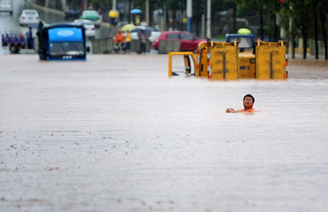 
Nước ngập tới cổ người đàn ông trên một con đường ở thành phố Cửu Giang.
