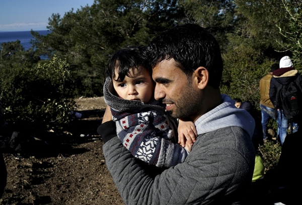 
Một người cha đang ôm con mình đứng chờ dọc một con đường gần bờ biển phía tây Thổ Nhĩ Kì, sau khi Thổ Nhĩ Kì cấm người tị nạn ra các đảo của Hy Lạp bằng thuyền.
