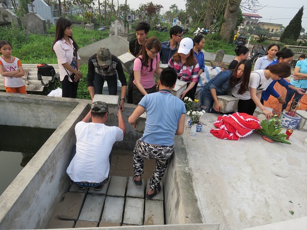 
Các tình nguyện viên đặt quan tài xuống hố chôn tập thể cho các hài nhi. Ảnh: ML
