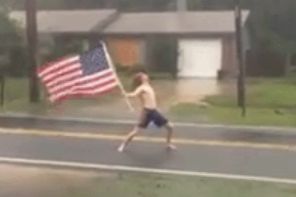 
Chàng trai cởi trần cầm cờ Mỹ trong cơn bão Matthew.
