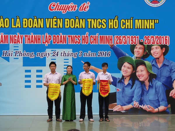 
TS Nguyễn Thị Lệ -hiệu trưởng nhà trường (áo dài xanh) tặng cờ thi đua cho các lớp xuất sắc. Ảnh: ML
