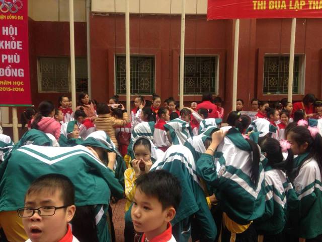 
Do chờ đợi quá lâu, nhiều em học sinh đã phải lấy áo khoác che mưa.
