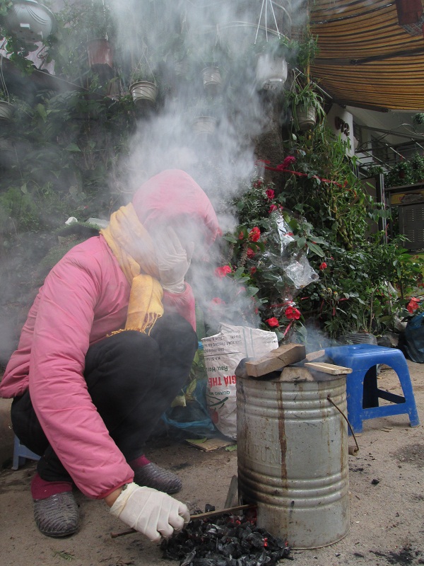 
Một phụ nữ khác đang chật vật với bếp than trên phố.

 
