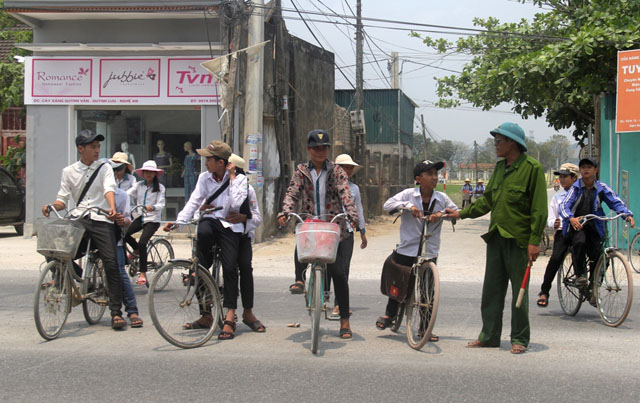 Như đã thành thói quen, mặc dù nhiều em đã lớn nhưng vẫn đợi hiệu lệnh của ông Cầm cho phép rồi mới qua đường. Ảnh: Phan Ngọc