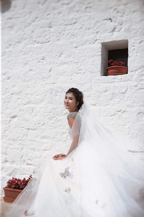 Người đẹp cười rạng rỡ khi hóa thành cô dâu trong thiết kế trắng kết hợp khăn voan bồng bềnh.