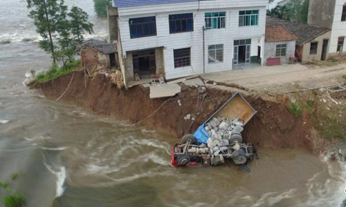 
Những chiếc xe tải chở đ&aacute; hộc lao xuống nước để chặn đoạn đ&ecirc; vỡ. Ảnh:Chinanews
