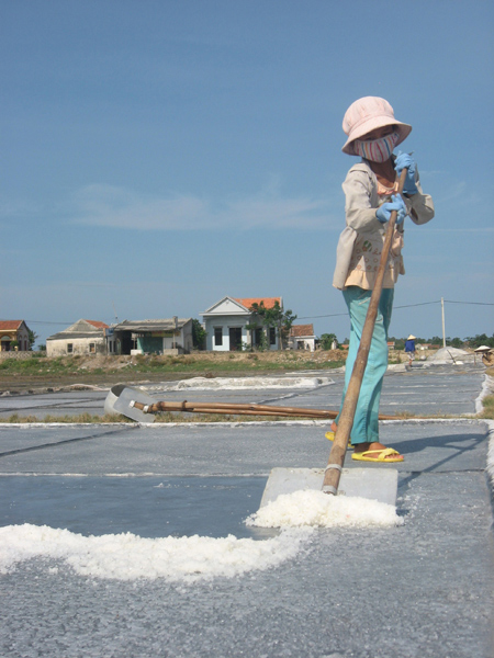 Ở cánh đồng muối An Hòa (Quỳnh Lưu, Nghệ An), em Nguyễn Thị Thắm tranh thủ những ngày nghỉ hè làm muối giúp bố mẹ. Thắm nói: Trời càng nắng, càng làm được muối, nên phải tranh thủ làm cả trưa. Ảnh: Hà Phương