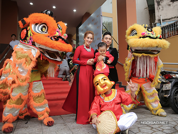 Khánh Thi mặc áo dài đỏ ton-sur-ton cùng con trai, trong khi Phan Hiển mặc vest đen lịch lãm tại sự kiện.