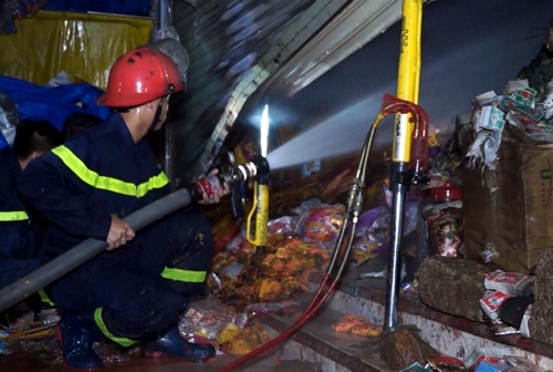 Cảnh s&aacute;t nỗ lực dập tắt đ&aacute;m ch&aacute;y trong căn nh&agrave; kinh doanh v&agrave;ng m&atilde;. Ảnh: Xu&acirc;n Mai