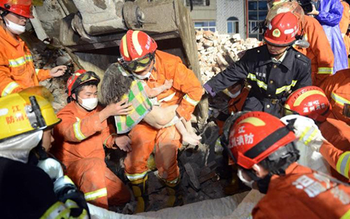 
Lính cứu hỏa bế cô bé 3 tuổi ra khỏi ngôi nhà sập ở thành phố Ôn Châu. Ảnh: AFP
