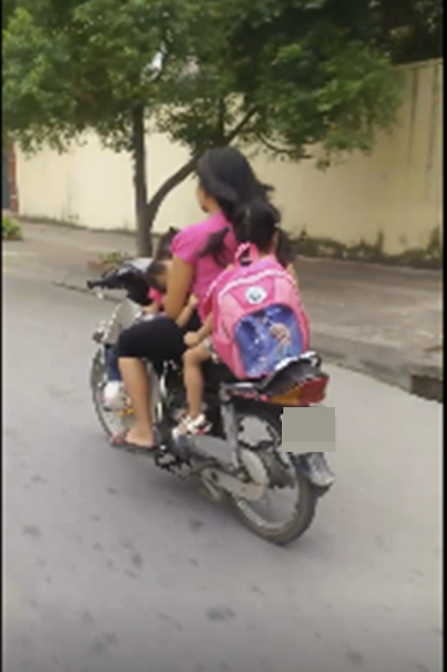 Người phụ nữ chở theo 3 con kh&ocirc;ng đội mũ bảo hiểm. Ảnh cắt từ clip