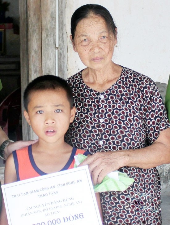 Ch&aacute;u H&ugrave;ng v&agrave; b&agrave; ngoại nhận qu&agrave; của tử t&ugrave; Thu từ tay c&aacute;n bộ trại giam C&ocirc;ng an tỉnh Nghệ An chuyển tới. Ảnh: Đ.L.