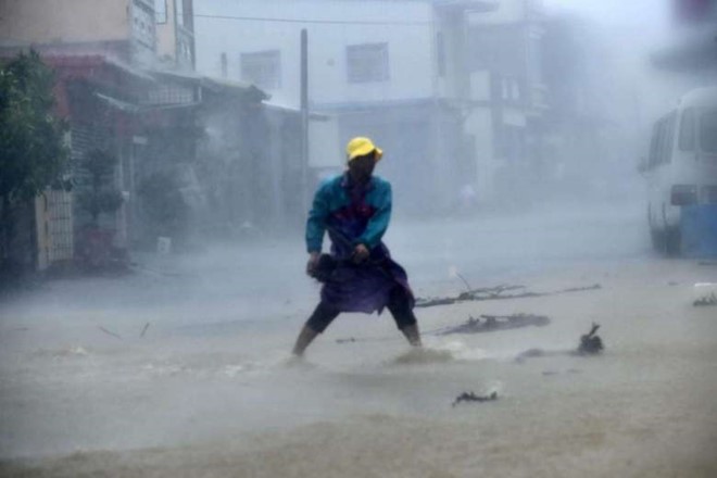 
Một người dân ở huyện Bình Đông dọn dẹp đá và chướng ngại vật trên một con đường trong mưa bão. Theo CNN, đã có 2 người bị thương do bão Meranti. Ảnh: AFP.
