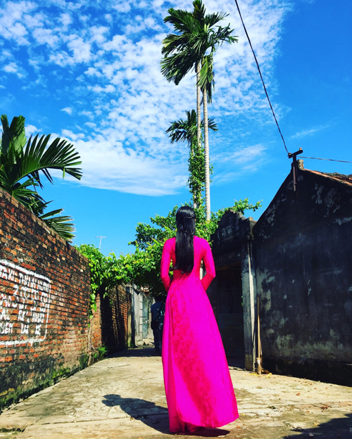 
Cô diện áo dài hồng rực, dạo bước trong khung cảnh yên bình của làng quê.
