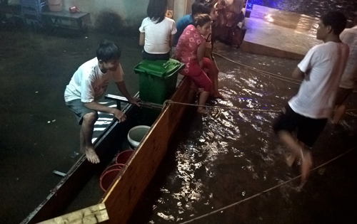 Một gia đình dùng ván cắn trước cửa để ngăn dòng nước ập vào nhà. Ảnh: Duy Trần