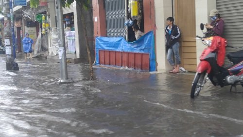 Một cửa hàng kinh doanh bên đường Bạch Đằng dùng ván, bạt chắn trước cửa nhà ngăn nước tràn vào nhà