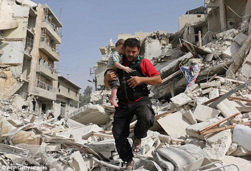
Một người đ&agrave;n &ocirc;ng Syria &ocirc;m theo một em b&eacute; tho&aacute;t khỏi đống đổ n&aacute;t của một t&ograve;a nh&agrave; bị ph&aacute; hủy sau cuộc tấn c&ocirc;ng tại khu phố Qatarji Aleppo
