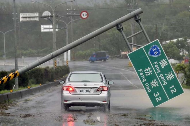 
Một chiếc xe đi dưới cột biển báo ngã đổ do bão. Nhiều chuyến bay và tàu bị hoãn, ảnh hưởng đến việc đi lại nghỉ Trung Thu của người dân Đài Loan. Kỳ nghỉ này kéo dài 4 ngày, bắt đầu từ thứ năm. Ảnh: AFP.
