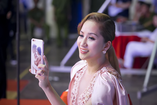 
Cô mỉm cười khi dùng điện thoại quay lại tiết mục trình diễn của ông xã Phan Hiển.
