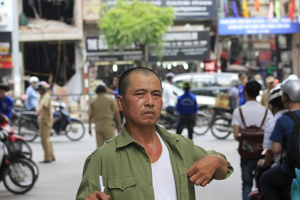 Người cha quạt mát cho con ôn bài trước đó đi lại chờ đợi con ra lúc sắp hết giờ thi. Ảnh: Q.A