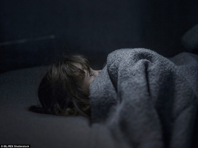 Fara, 2, lies under a blanket in a makeshift bed in Azraq, Jordan. A massive football fan, her father every night says goodnight in the hope he will find a football for her to play with the following day