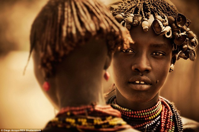 Beauties: Two young girls wearing traditional bead necklaces and with shells woven in their hair take a moment to enjoy a gossip 