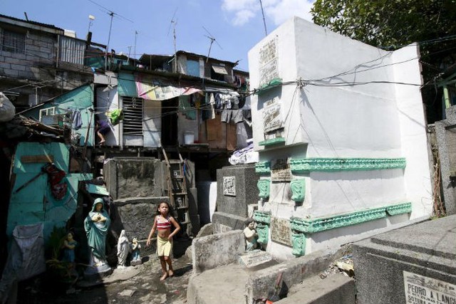 
Những ngôi mộ bỏ hoang được người dân nghèo biến thành nhà ở. Ảnh: Bé gái đi bộ trước cửa nhà tại nghĩa trang nhân dân Nam Manila ở thành phố Pasay ngày 30/10/2015.
