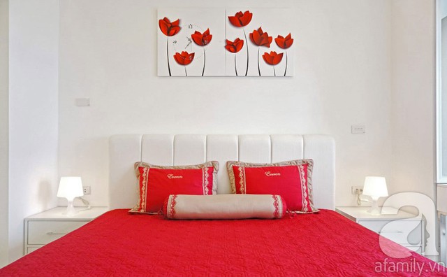 Phòng ngủ nổi bật với bộ ga gối đệm và bức tranh hoa đỏ lãng mạn.