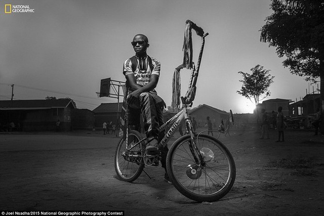 Tác phẩm của nhiếp ảnh gia người Mỹ - Joel Nsadha. Mang tựa đề At the Playground (Tại sân chơi) là hình ảnh chàng trai tên Bwengye sống trong khu ổ chuột Kamwokya, thủ đô Kampala, Uganda bên chiếc xe đạp, theo dõi các em nhỏ đá bóng.