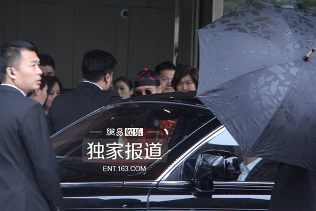 Thượng Hải đổ mưa vào sáng 8/10. Huỳnh Hiểu Minh (áo đỏ, kính đen, mũ nồi) giúp cô dâu vào xe hoa.