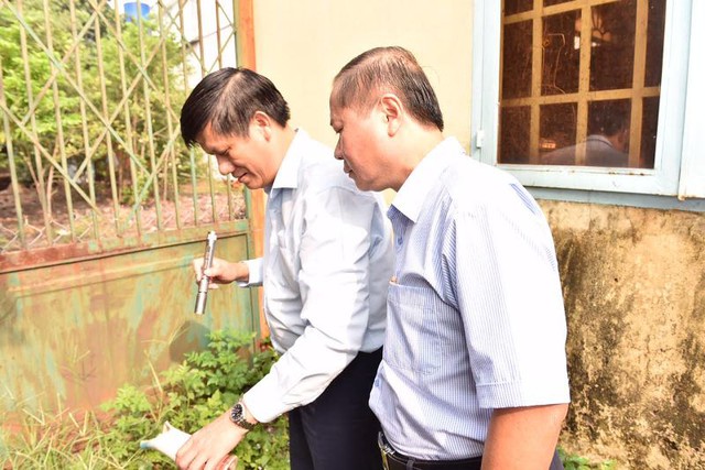 Thứ trưởng Y tế Nguyễn Thanh Long (trái) đang đổ nước trong lọ hoa chứa nhiều bọ gậy tại một hộ gia đình khi giám sát hoạt động phòng chống dịch bệnh sốt xuất huyết tại Đồng Nai sáng 18/9.
