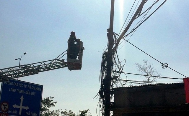 C&aacute;c chiến sĩ cứu hộ tiếp cận nam thanh ni&ecirc;n tr&egrave;o cột điện. Ảnh: Nguy&ecirc;n Hải.