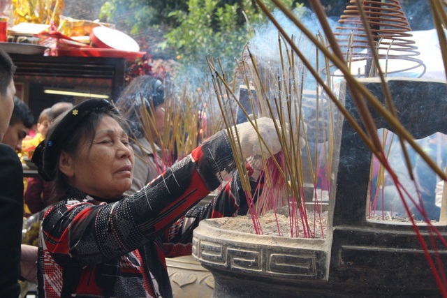 
Một người làm việc trong đền đang nhổ đi những nén hương người dân vừa thắp để đảm bảo vệ sinh trong đền.
