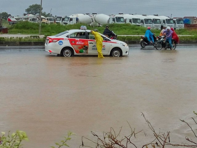 
Một người ra hướng dẫn một xe taxi quay đầu vì khu vực này nước lên cao không thể di chuyển qua được.
