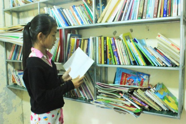 Em Phan Thị Vân, lớp 4/1 Trường tiểu học Phú Đa 3, tham khảo sách tại Tủ sách yêu thương. Ảnh: Tuổi Trẻ.