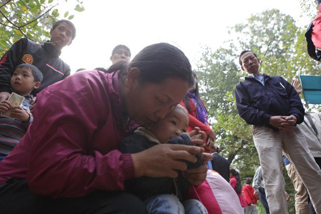 Người lớn dạy trẻ nhỏ chắp tay thành kính trước tấm bia đá, tưởng nhớ vua Quang Trung trên gò Đống Đa