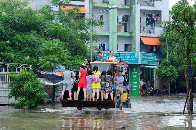 Người dân trèo máy xúc để rời khỏi khu ngập ở KĐT Resco Bắc Từ Liêm. Ảnh: Phạm Hải