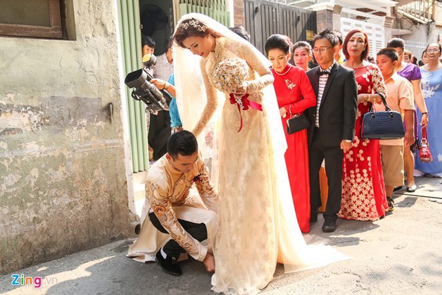 
Trên đường ra xe đưa cô dâu về Tiền Giang, Lương Thế Thành vội vàng ngồi xuống, chỉnh giày cho vợ khi cô vấp phải tà áo dài.
